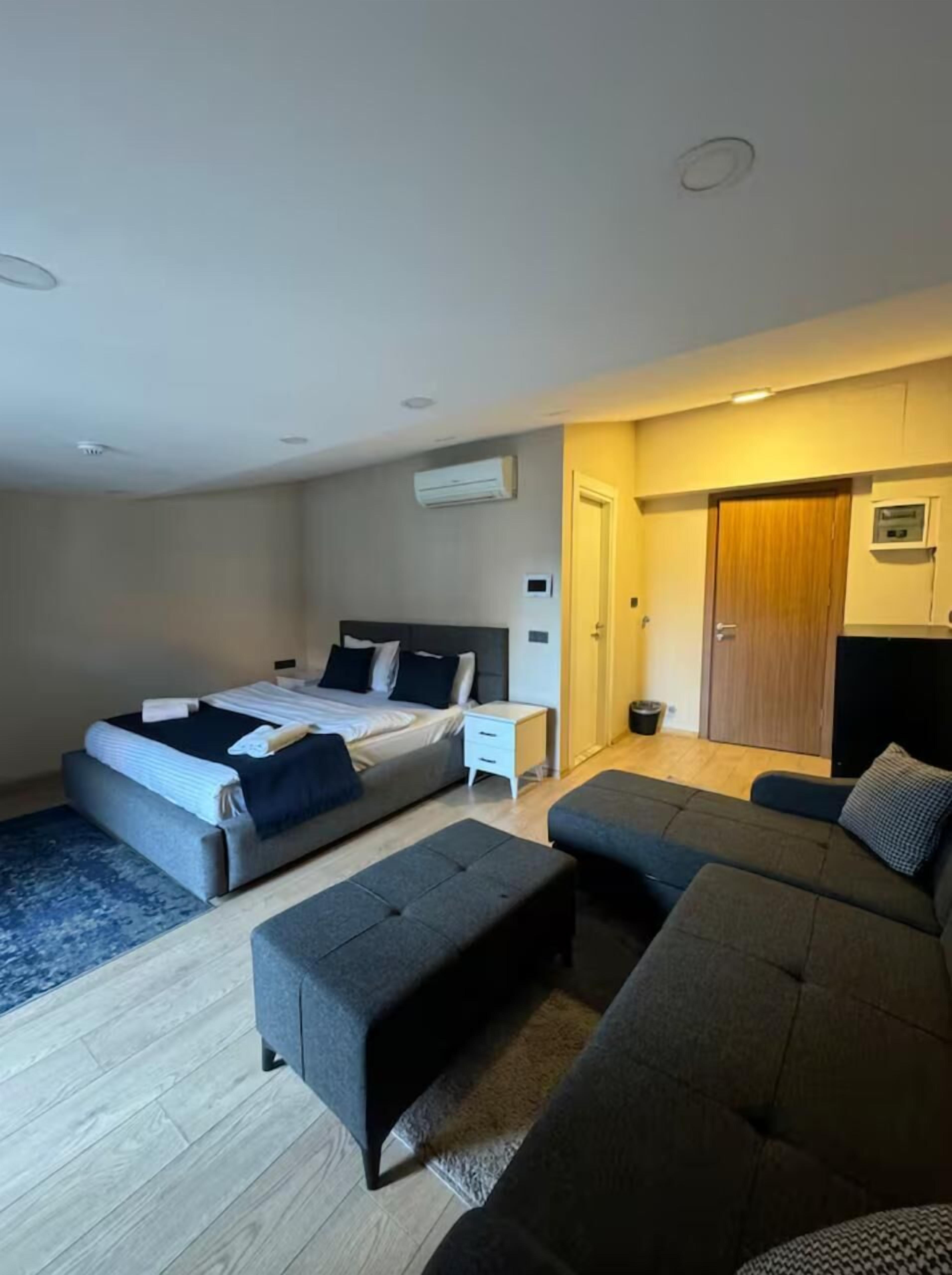 Une chambre moderne avec un lit, un canapé, une petite table et un appareil de climatisation fixé au mur.