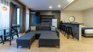 A modern hotel room with a sectional sofa, a dining area with bar stools, a kitchen counter, and a large window with curtains. - the business class suit karkoy (Istanbul)