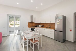Eine moderne Küche mit weißen Schränken, einer Holz Arbeitsplatte und einem Edelstahl-Kühlschrank.