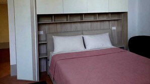 Een slaapkamer met een bed, een kledingkast en een stoel.