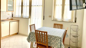 A compact kitchen with a dining area, a TV mounted on the wall, and a small cabinet. - Cefalù Pirandello House, very spacious facility, close to the sea and the center (Cefalù)