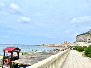 Eine Küstenlandschaft mit Strand, einem Rettungsschwimmturm und einer Kirche auf einem Hügel.