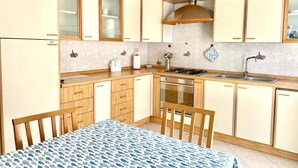 A compact kitchen with wooden cabinets, a gas stove, and a sink. - Cefalù Pirandello House, very spacious facility, close to the sea and the center (Cefalù)