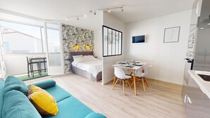 A modern, well-lit apartment with a bed, a dining area, and a living room with a sofa. - Le Grain de Sel (Saint-Hilaire-de-Riez)