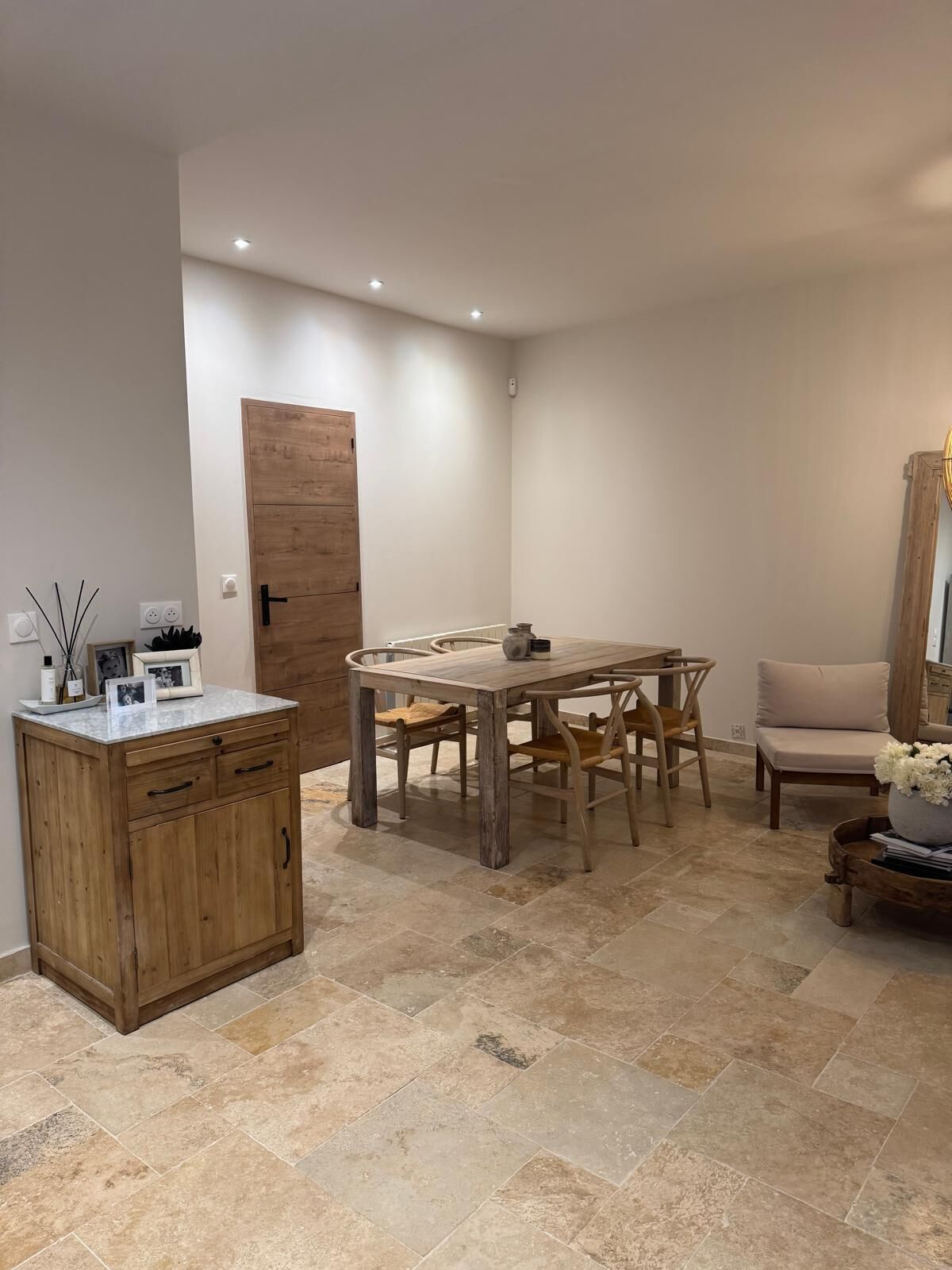 Un coin repas avec une table et des chaises en bois, un buffet en bois et un canapé beige.