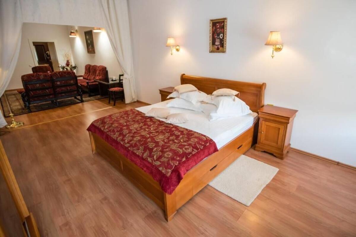 Un dormitorio con una cama de madera, una colcha roja, dos mesitas de noche y un aparador.