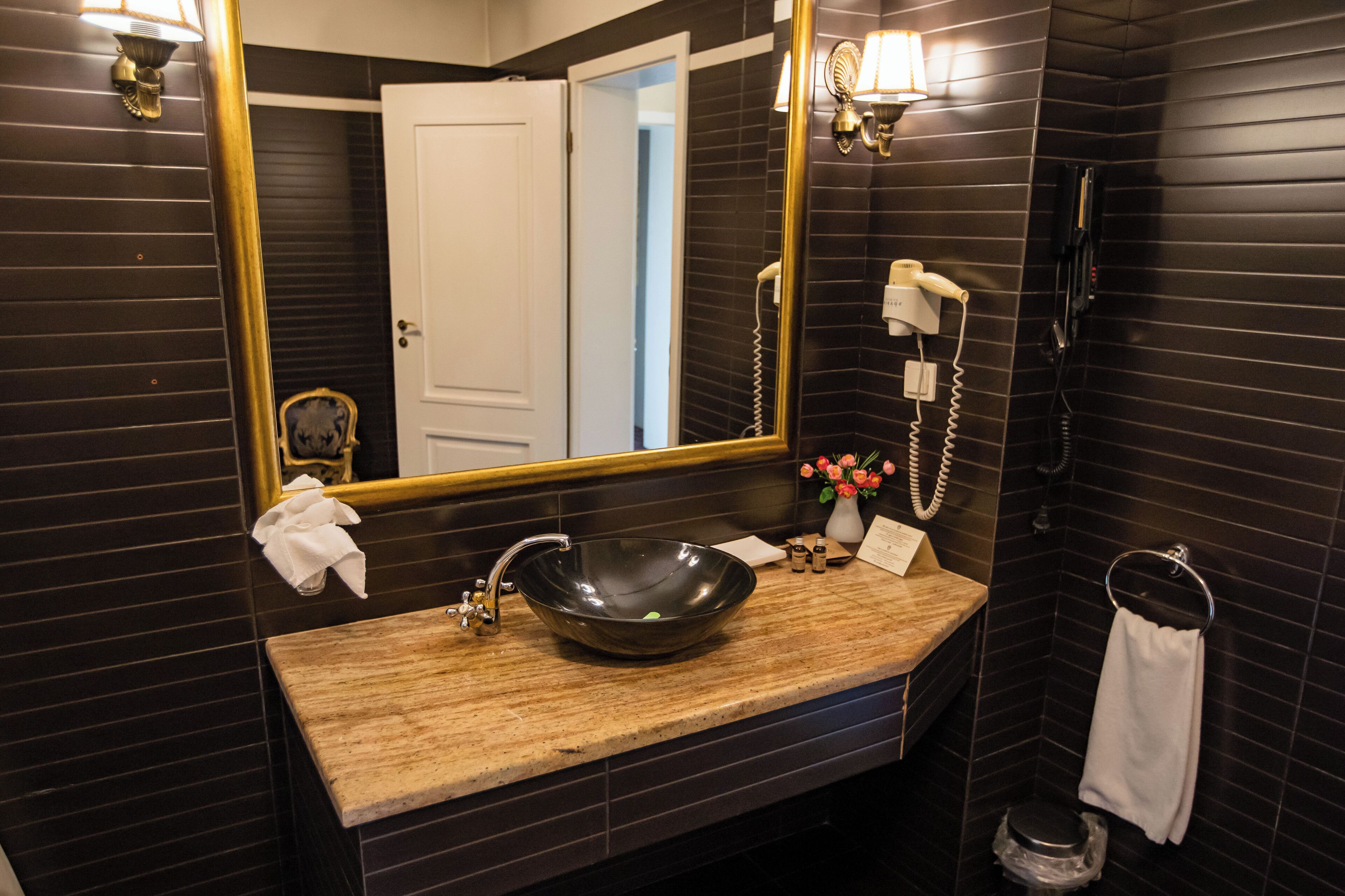 Une salle de bain avec un meuble-lavabo en bois, un grand miroir, un sèche-cheveux et des toilettes.