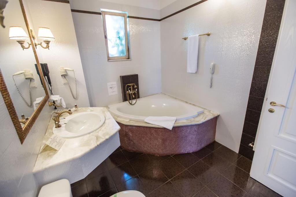 Une salle de bain avec une grande baignoire, un lavabo et un miroir.