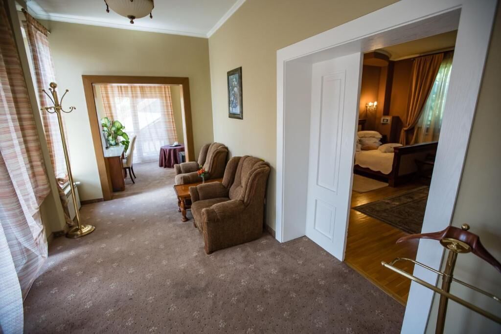 A hotel room with a sitting area, a dining table, and a bedroom.