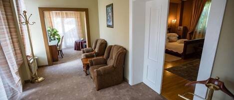 A hotel room with a sitting area, a dining table, and a bedroom.