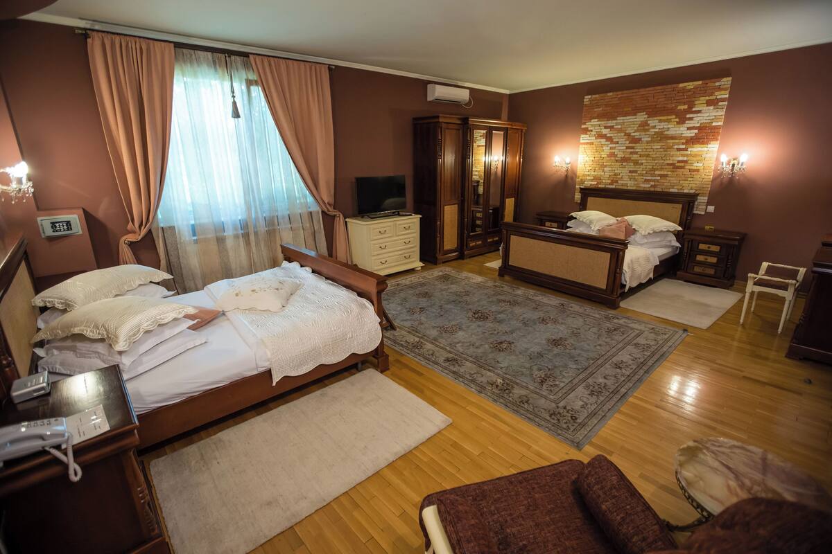 Un dormitorio con una cama de madera, un aparador, un armario, un televisor y una alfombra estampada.