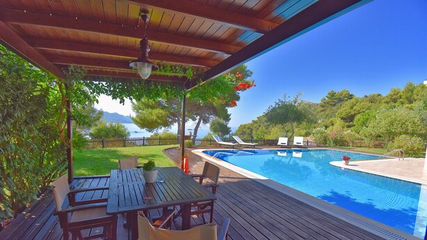 A wooden deck with a pool, outdoor seating, and a view of the sea. - Villa Pasiphae (Corfu)