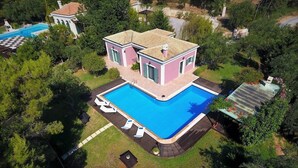 A two-story house with a swimming pool, surrounded by trees and a fenced yard. - Villa Pasiphae (Corfu)