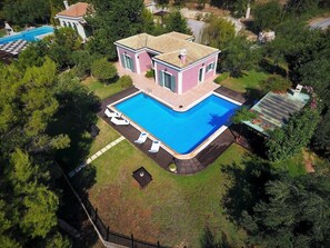 Ein zweistöckiges Haus mit Swimmingpool, umgeben von Bäumen und einem eingezäunten Garten.