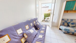 Una stanza con un divano viola con cuscini decorati, un divano blu con cuscini decorati e un pavimento piastrellato bianco.