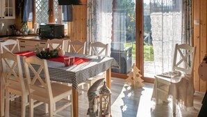 A cozy dining area with a checkered tablecloth, wooden chairs, and a view through a glass door. - Holiday Home With Sauna, Jacuzzi, Private Pond (Lipusz)