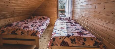 Eine kleine Holzhütte mit zwei Einzelbetten, jeweils mit Blumenmuster bezogen.