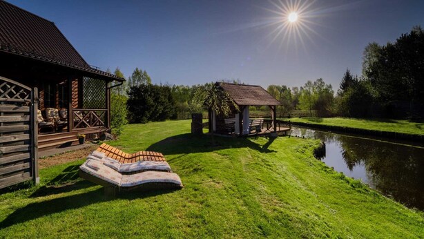 A wooden cabin with a porch and a small gazebo by a pond. - Holiday Home With Sauna, Jacuzzi, Private Pond (Lipusz)