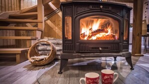 A cozy room with a wood-burning stove, a woven basket, and two mugs on a glass table. - Holiday Home With Sauna, Jacuzzi, Private Pond (Lipusz)