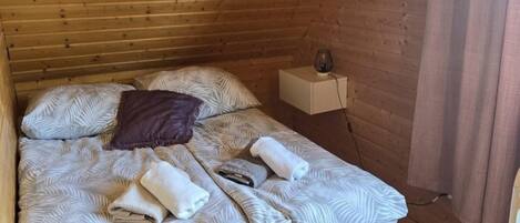 Una cama con ropa de cama estampada, una almohada y toallas enrolladas.