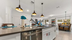 Een moderne keuken met roestvrijstalen apparatuur, hanglampen en een groot eiland.