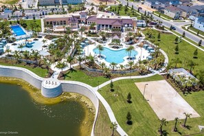 Una vista aerea di un resort con diverse piscine, un'ampia vasca d'acqua e prati curati.