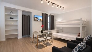 A modern, well-lit room with a bunk bed, a dining area with chairs and a table, and a sofa with patterned cushions. - Coastal Retreat Charming 1bdr MiamiBeach (Miami Beach)