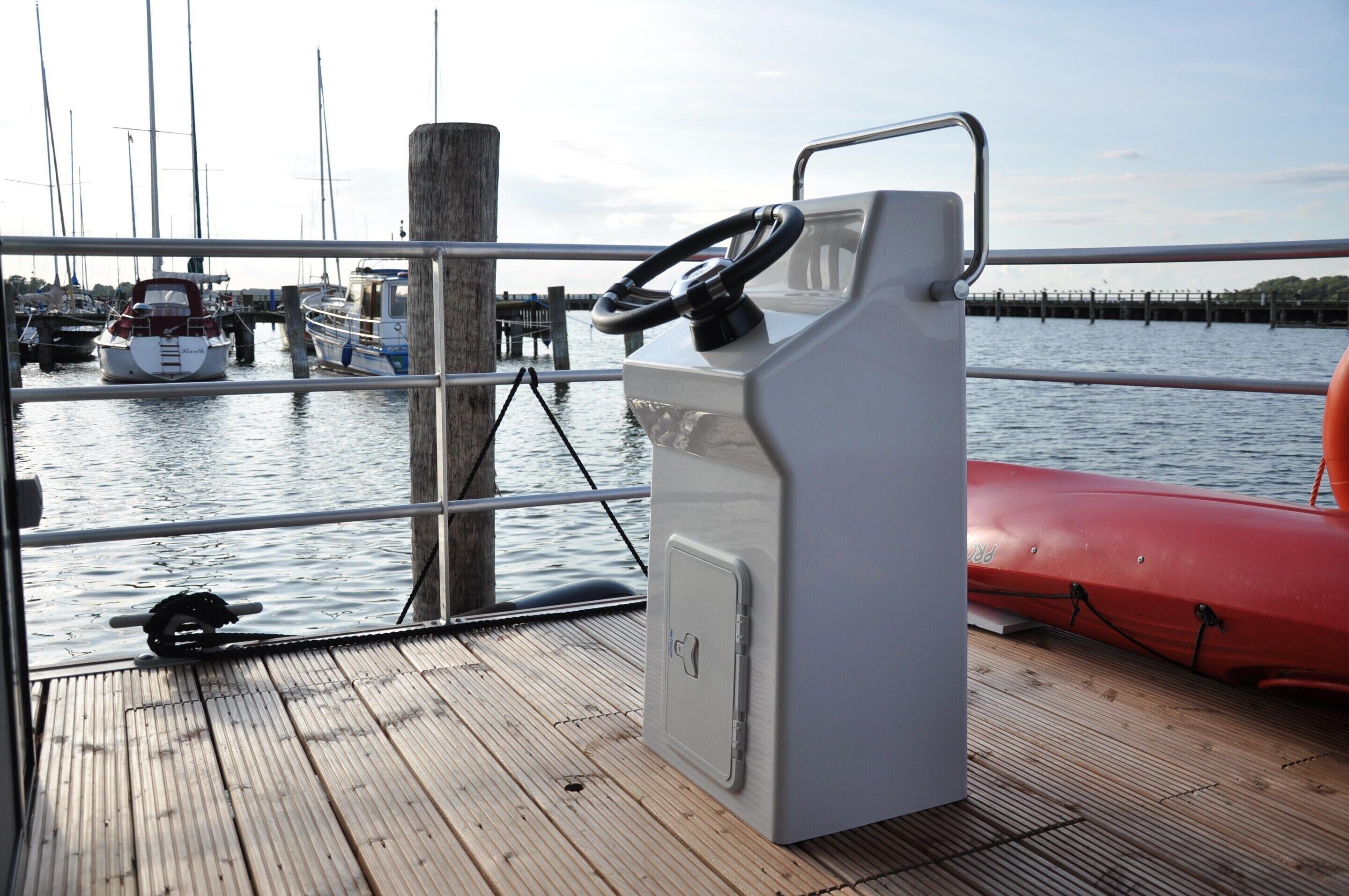 A boat's deck with a steering wheel, a life preserver, and a metal railing.
