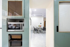 A compact kitchen with a microwave, a small refrigerator, and a wicker basket. - Tranquil 3-bedroom apartment with AC in vibrant Vishakapatnam (vishakapatnam)