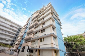 A multi-story residential building with balconies, air conditioning units, and a visible entrance.