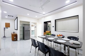 A modern dining area with a table set for four, a refrigerator, and a ceiling fan.