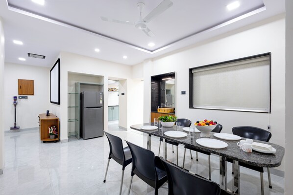 A modern dining area with a table set for four, a refrigerator, and a ceiling fan.