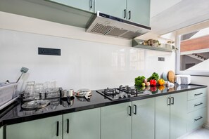 A modern kitchen with a gas stove, cabinets, and a window overlooking a staircase.