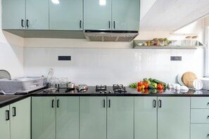 A kitchen with light green cabinets, a gas stove, and various kitchen utensils.