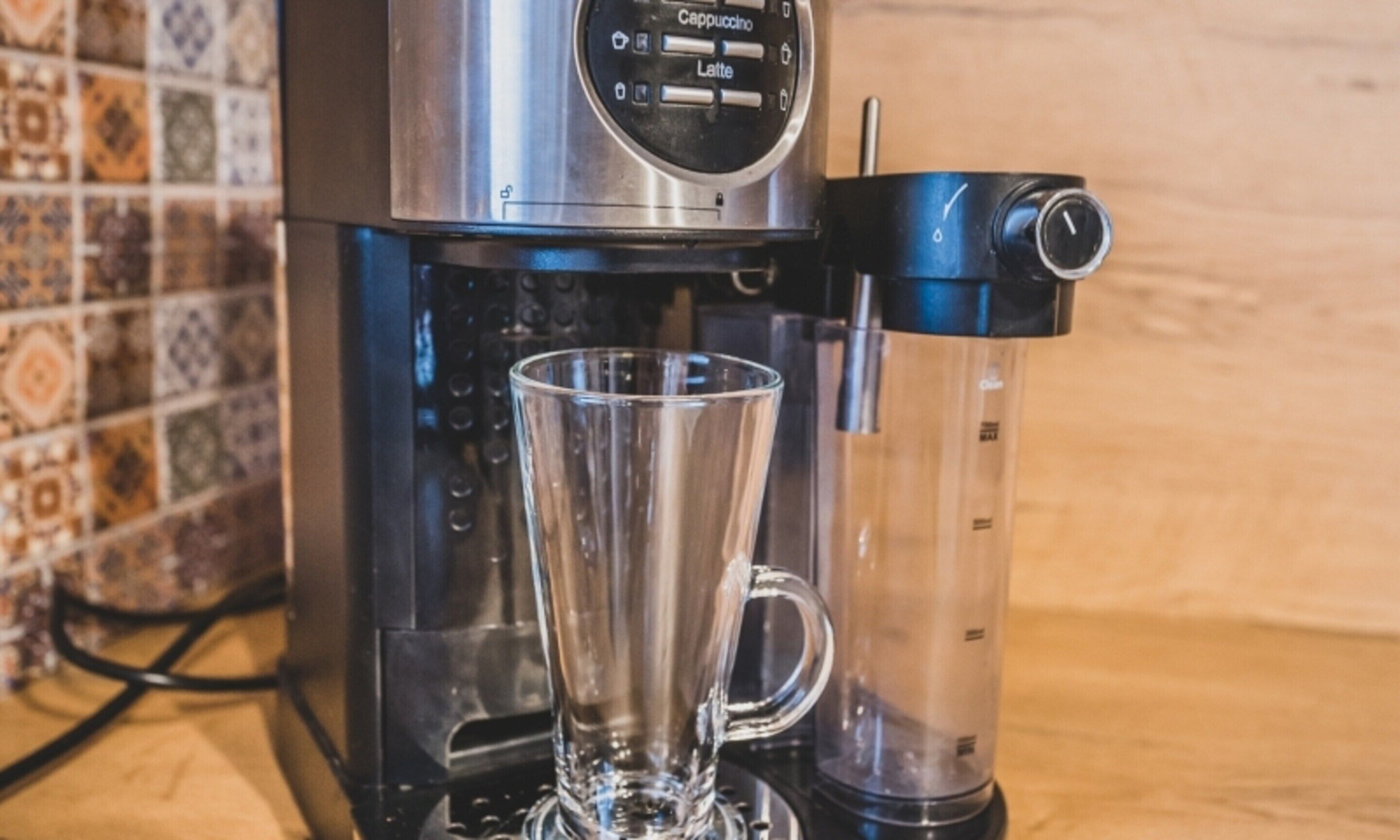 A coffee maker with a glass cup placed on its drip tray.
