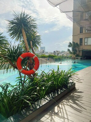 Une piscine extérieure équipée d’une bouée de sauvetage, entourée de verdure et avec une vue sur la ville en arrière-plan.