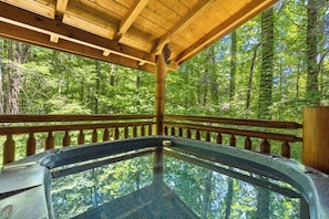 Un bain à remous dans un gazebo en bois, entouré d’une forêt.