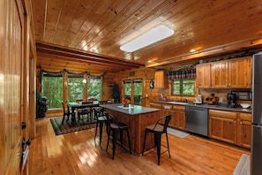 L’intérieur d’un chalet en bois comprend une cuisine, un coin repas et un bar.