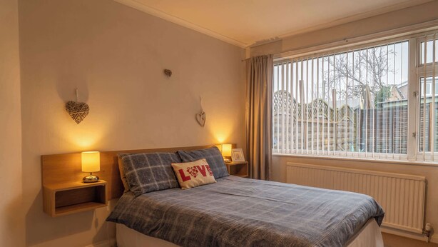 A bedroom with a bed, two bedside tables with lamps, a window with curtains, and decorative wall art. - No 48 - 3 Bedroom Heworth in York (York)