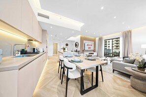 A modern kitchen with a central island, a dining area with a 'BOOK ME' sign, and a living room with a sofa and a view of the city. - A Free Housekeeping Visit FOR Every Stay Between THE 16th FEB AND THE 16th MAR - Stayshort - 1 Bed in Downtown Dubai That Sleeps 4 With Balcony (Dubai)