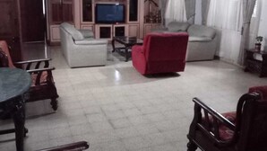 Ein Wohnzimmer mit Fernseher, Sofa und Sesseln.