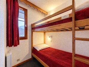 A bunk bed room with a window, a red curtain, and a wall-mounted light fixture. - Val d'Isère - 3-room apartment, 6 pers, pets allowed (Val-d'Isère)