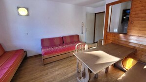 En kompakt bolig med trægulv, sofa, spisebord og et spejl.