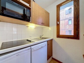 A compact kitchen with a microwave, dishwasher, and a window with a view of a building. - Val d'Isère - 3-room apartment, 6 pers, pets allowed (Val-d'Isère)