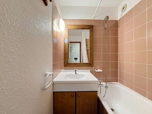 A bathroom with a white sink, wooden cabinet, and a shower with a handheld showerhead. - Val d'Isère - 3-room apartment, 6 pers, pets allowed (Val-d'Isère)
