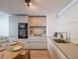 A compact kitchen with a dining area, a built-in oven, a sink, and a kettle. - Elegant apartment at the foot of the slopes, Alpe d'Huez (Huez)