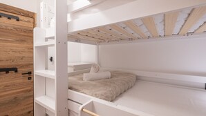 A bunk bed with a wooden headboard, white walls, and a wooden ceiling. - Elegant apartment at the foot of the slopes, Alpe d'Huez (Huez)