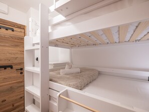 A bunk bed with a wooden headboard, white walls, and a wooden ceiling. - Elegant apartment at the foot of the slopes, Alpe d'Huez (Huez)