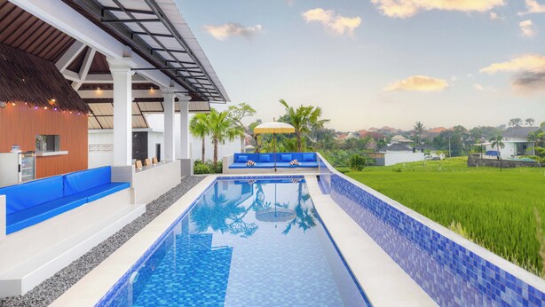 A modern pool area with a clear view of a lush green landscape and a distant village. - Gangga Homestay Pererenan (Munggu)
