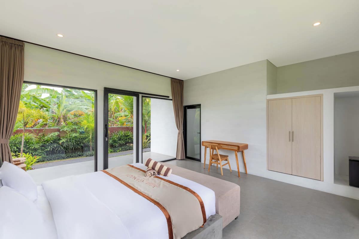 A modern hotel room with a large bed, a desk, and a wardrobe.